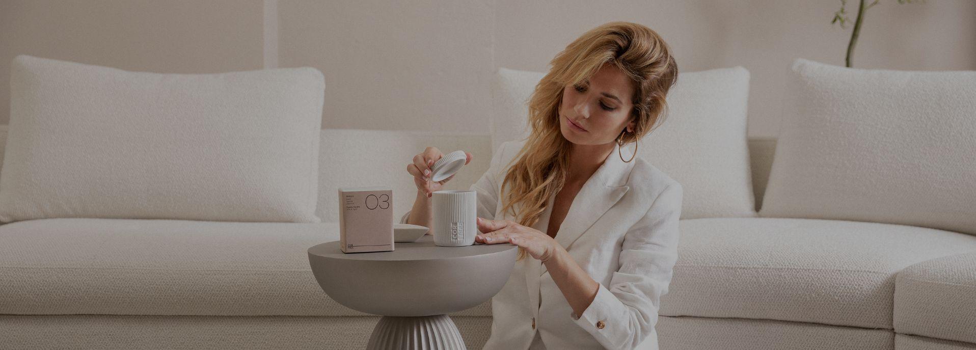 Mujer abriendo una vela aromática Cortell 03 Andreia en el salón, junto a su estuche
